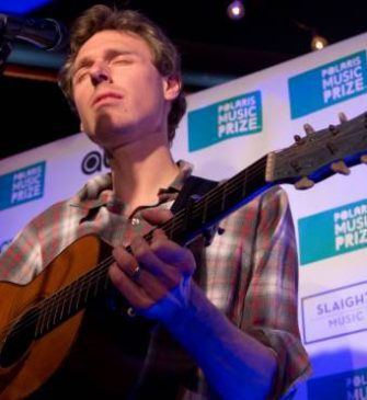 Joel Plaskett performing at Polaris Music Prize, eyes shut, playing acoustic guitar